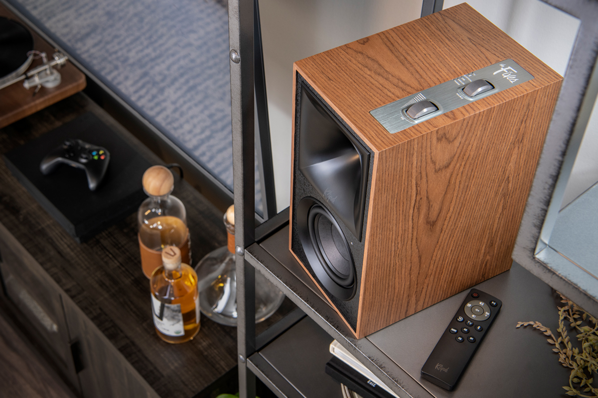 Top view of Klipsch the Fives walnut speaker next to Klipsch the Fives IR Remote